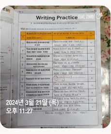 수강생 인증 사진 — Writing Practice 영작 칸을 손글씨로 채우고 빨간펜으로 고친 페이지. 2024년 3월 21일 목요일 오후 11시 27분